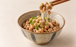 一小碗日式納豆，筷子拉起細長黏絲
